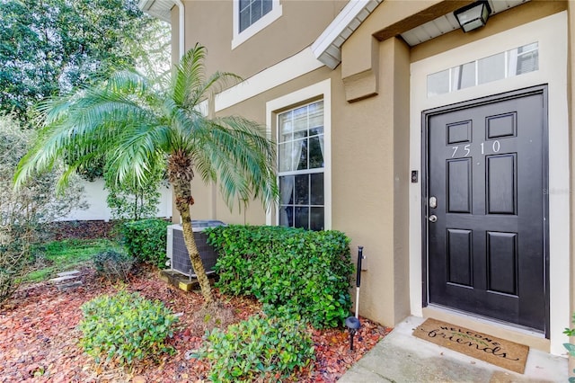 view of exterior entry featuring stucco siding and central AC