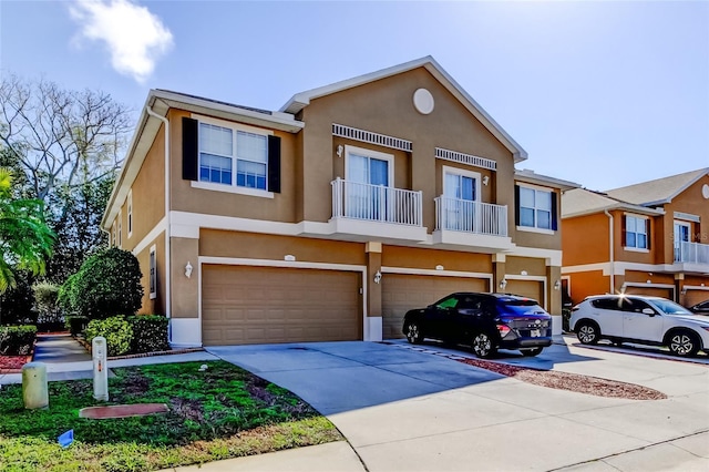 view of front of home with stucco siding, an attached garage, driveway, and a balcony