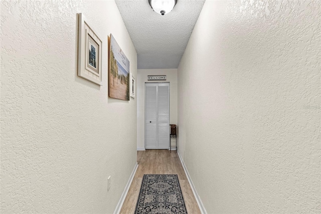 hallway with hardwood / wood-style floors and a textured ceiling