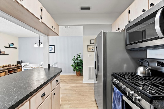 kitchen featuring appliances with stainless steel finishes, light brown cabinetry, decorative light fixtures, an inviting chandelier, and light hardwood / wood-style flooring