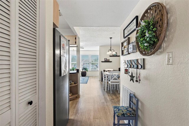 corridor with hardwood / wood-style flooring and a textured ceiling