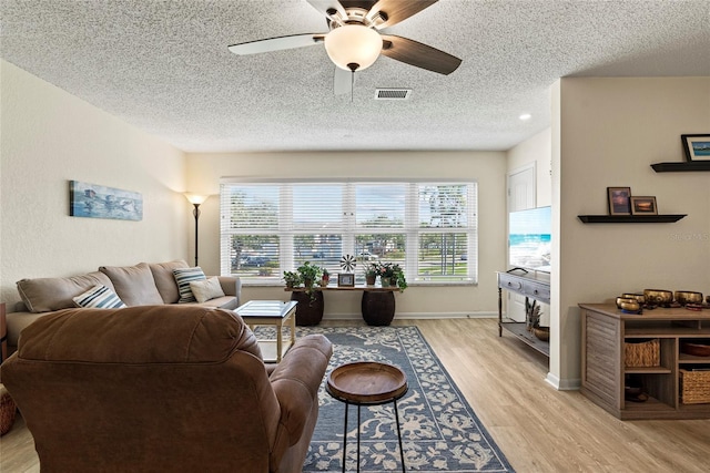 living room with ceiling fan, light hardwood / wood-style floors, and a textured ceiling