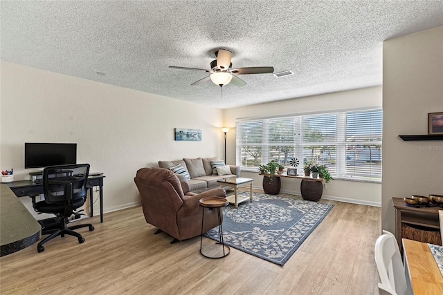 living room with a textured ceiling, light hardwood / wood-style floors, and ceiling fan