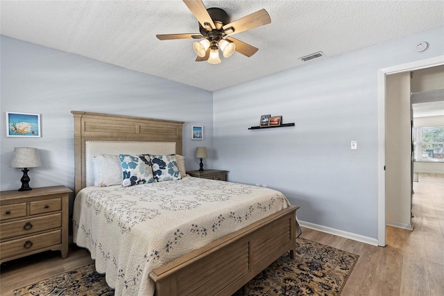 bedroom featuring ceiling fan, a textured ceiling, and light hardwood / wood-style flooring