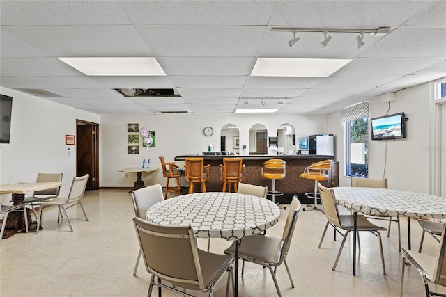 dining room featuring bar area and a drop ceiling