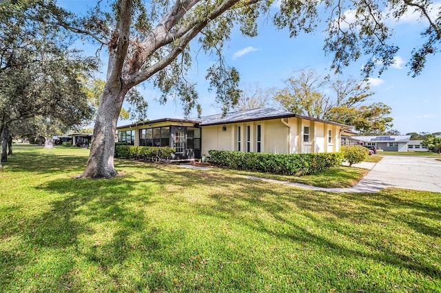 ranch-style home featuring a sunroom and a front yard