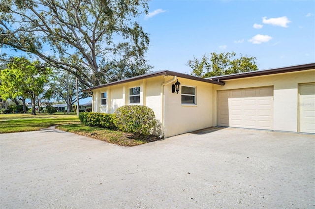 view of side of property featuring driveway, an attached garage, and stucco siding