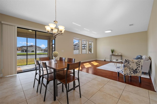 tiled dining area featuring a water view, a healthy amount of sunlight, and a chandelier