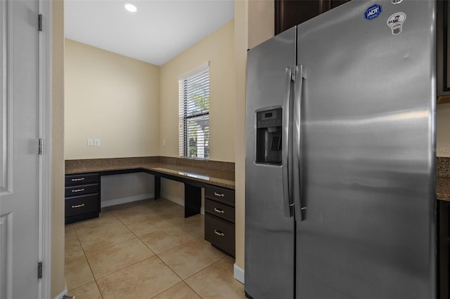 kitchen with stainless steel refrigerator with ice dispenser, built in desk, and light tile patterned floors