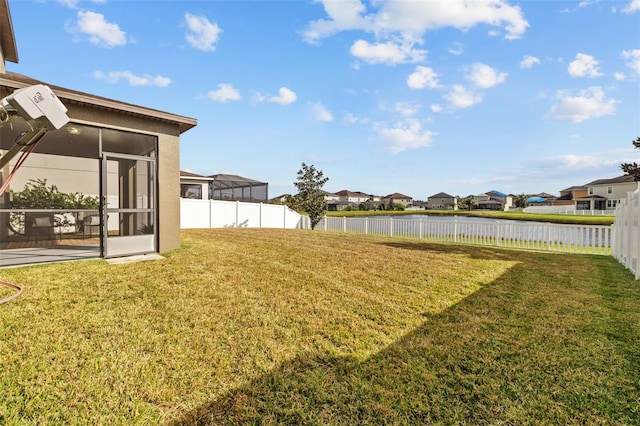 view of yard featuring a sunroom and a water view