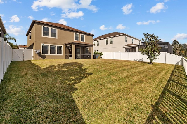 rear view of house featuring a lawn and a sunroom