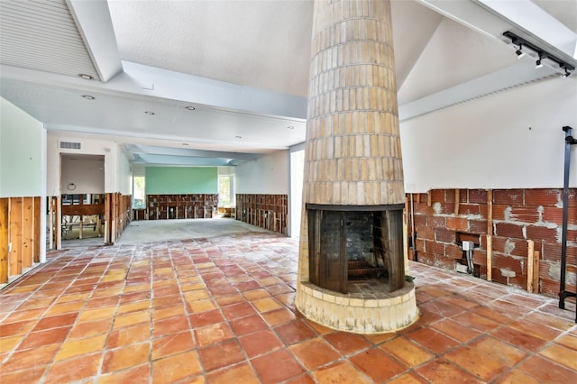 unfurnished living room with tile patterned flooring, rail lighting, and a brick fireplace