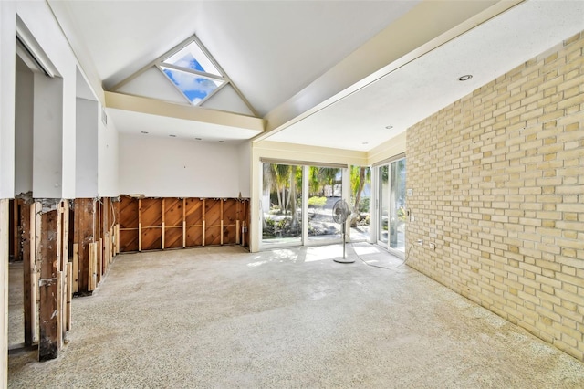 spare room featuring high vaulted ceiling, carpet, and brick wall