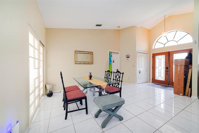 tiled dining room featuring high vaulted ceiling and french doors