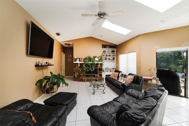 living room with light tile patterned floors, lofted ceiling with skylight, a textured ceiling, and ceiling fan