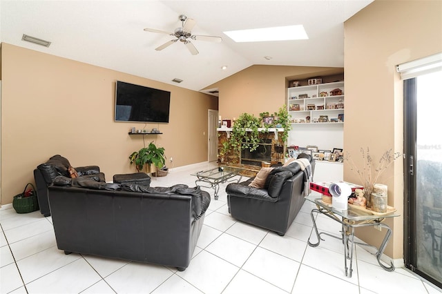 living room with ceiling fan, lofted ceiling with skylight, and light tile patterned floors