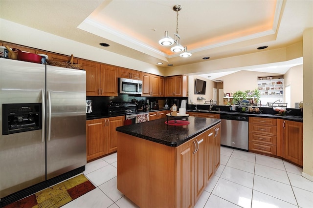 kitchen featuring a tray ceiling, a kitchen island, light tile patterned flooring, and appliances with stainless steel finishes