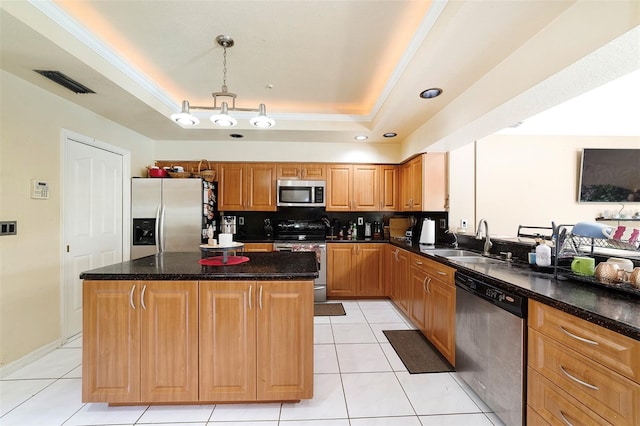 kitchen featuring sink, appliances with stainless steel finishes, hanging light fixtures, a tray ceiling, and a kitchen island