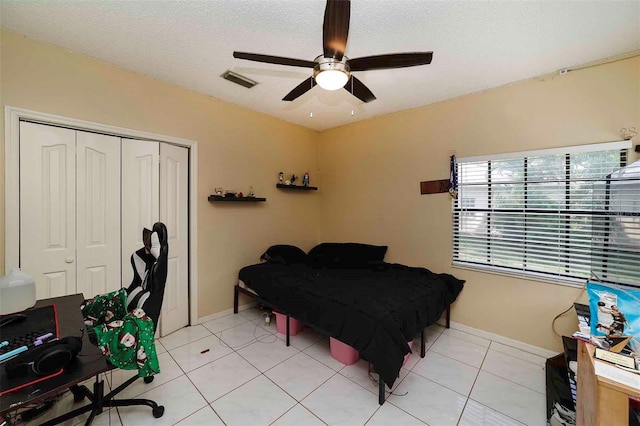 tiled bedroom with a textured ceiling, a closet, and ceiling fan