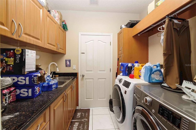 laundry area featuring light tile patterned flooring, sink, cabinets, washing machine and clothes dryer, and a textured ceiling