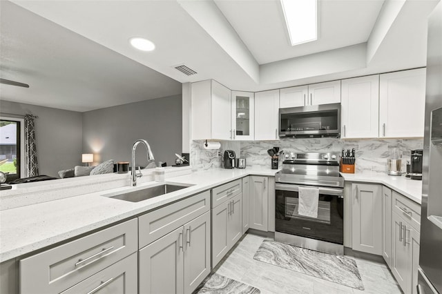 kitchen featuring sink, decorative backsplash, stainless steel appliances, and light stone countertops