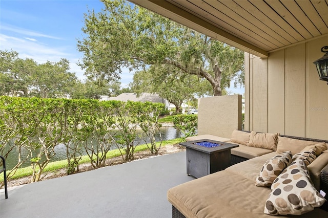 view of patio with an outdoor living space with a fire pit and a water view