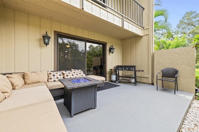 view of patio featuring a balcony and an outdoor living space with a fire pit