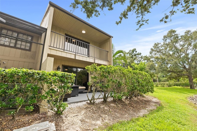 rear view of house featuring a balcony, a yard, and a patio area