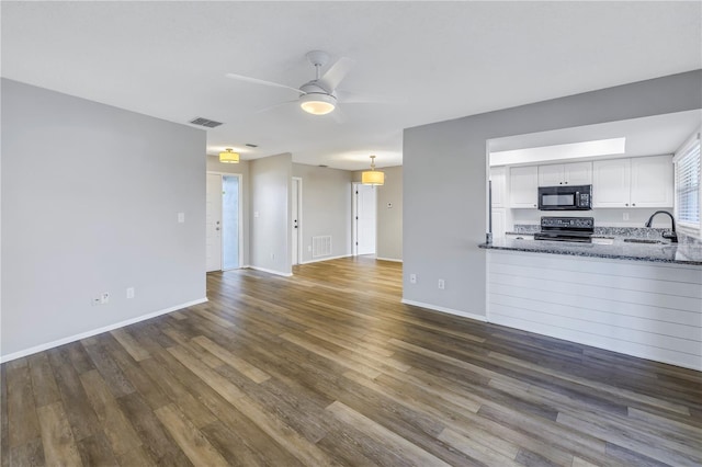 unfurnished living room featuring dark wood-type flooring, ceiling fan, and sink