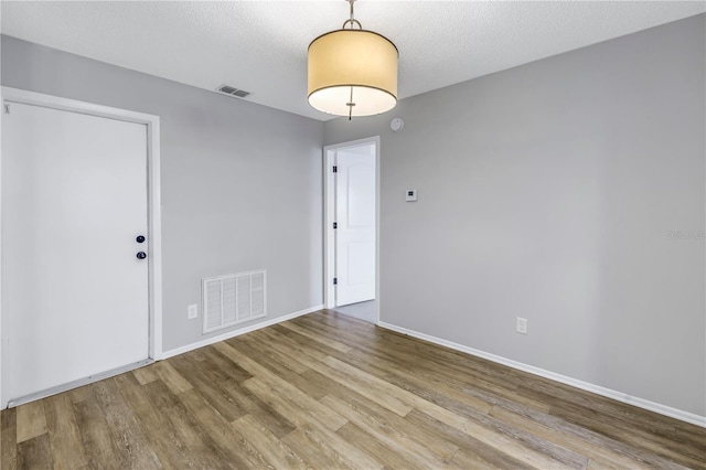 spare room with a textured ceiling and light wood-type flooring