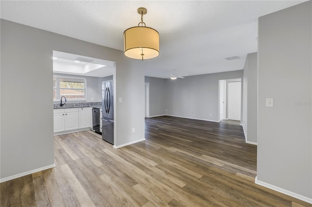 interior space featuring ceiling fan, sink, hardwood / wood-style floors, and a textured ceiling