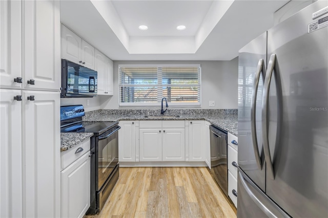 kitchen with sink, black appliances, a raised ceiling, light stone countertops, and white cabinets