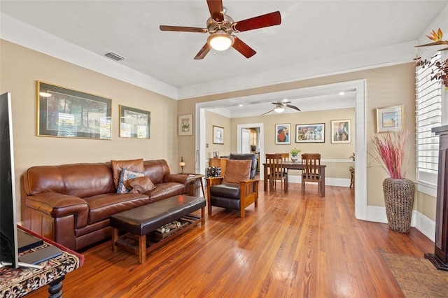 living room with hardwood / wood-style floors, crown molding, and ceiling fan