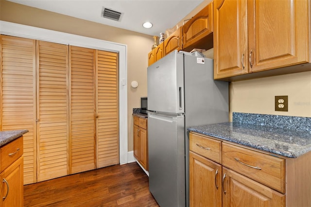 kitchen featuring stainless steel refrigerator, dark stone counters, and dark hardwood / wood-style flooring