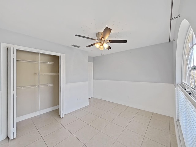 unfurnished bedroom featuring a closet, visible vents, ceiling fan, and light tile patterned floors