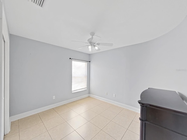 spare room featuring a ceiling fan, visible vents, baseboards, and light tile patterned floors