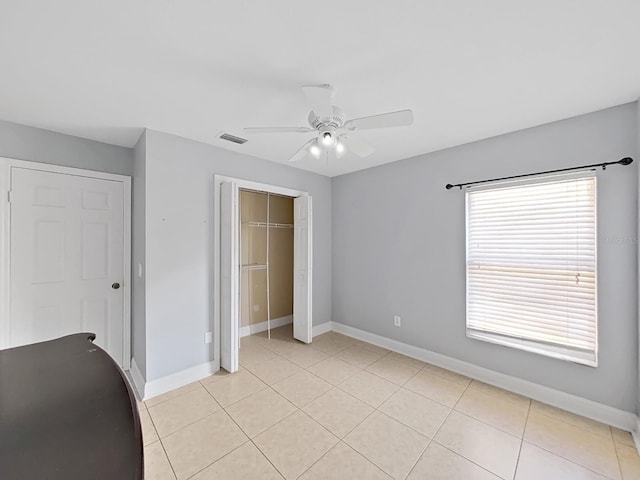 unfurnished bedroom featuring a closet, visible vents, a ceiling fan, light tile patterned flooring, and baseboards