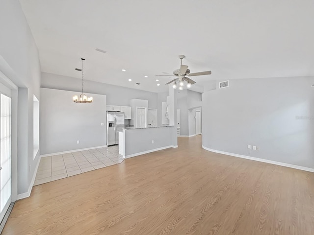 unfurnished living room with visible vents, light wood-style floors, vaulted ceiling, baseboards, and ceiling fan with notable chandelier