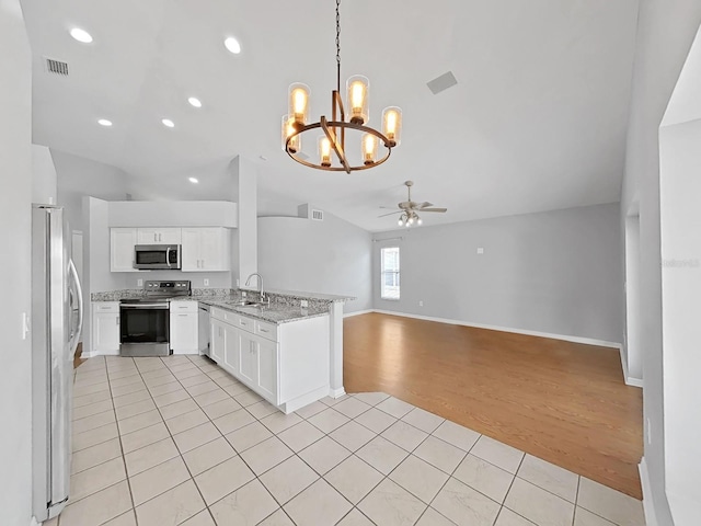 kitchen with decorative light fixtures, appliances with stainless steel finishes, open floor plan, white cabinets, and a sink