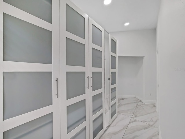 hall featuring baseboards, marble finish floor, and recessed lighting