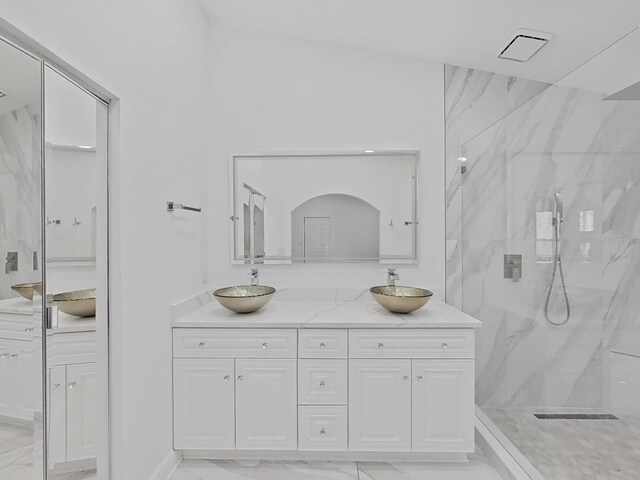 bathroom with marble finish floor, double vanity, a sink, and a marble finish shower