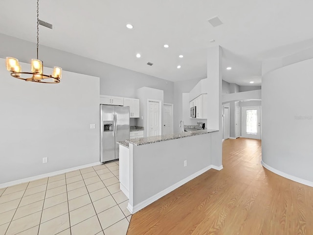 kitchen featuring light stone counters, hanging light fixtures, white cabinetry, a peninsula, and stainless steel fridge with ice dispenser