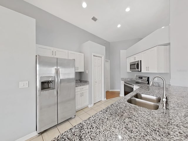 kitchen with light stone counters, white cabinetry, stainless steel appliances, and a sink