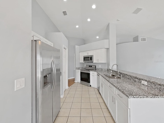 kitchen with stainless steel appliances, light stone counters, a sink, and white cabinetry