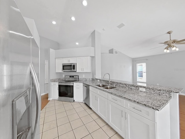 kitchen featuring a peninsula, appliances with stainless steel finishes, a sink, and white cabinets