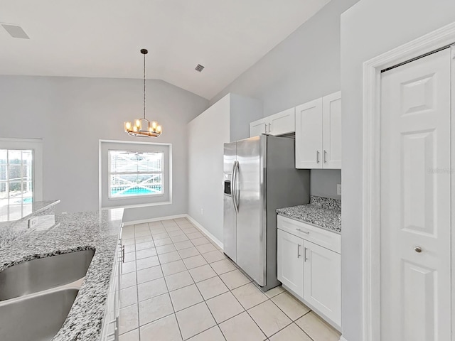 kitchen featuring white cabinetry, vaulted ceiling, stainless steel refrigerator with ice dispenser, light stone countertops, and plenty of natural light