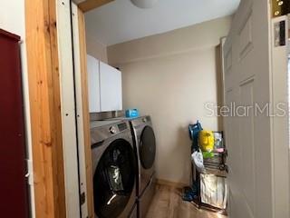 clothes washing area with cabinets and washer and dryer