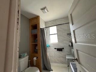 bathroom with toilet and a shower with shower curtain