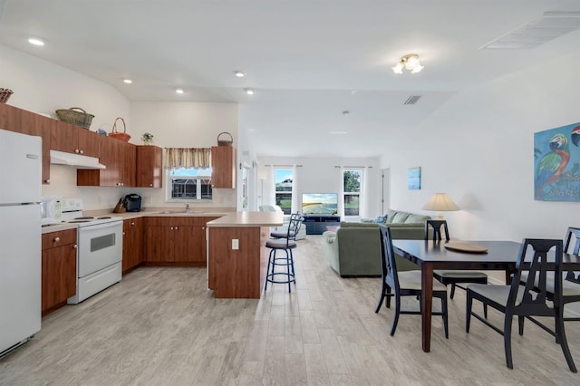 kitchen featuring a kitchen bar, sink, a kitchen island, white appliances, and light hardwood / wood-style floors