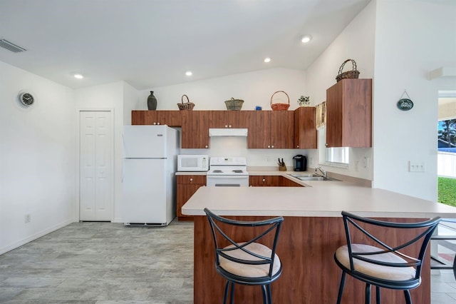 kitchen featuring sink, white appliances, a breakfast bar, vaulted ceiling, and kitchen peninsula